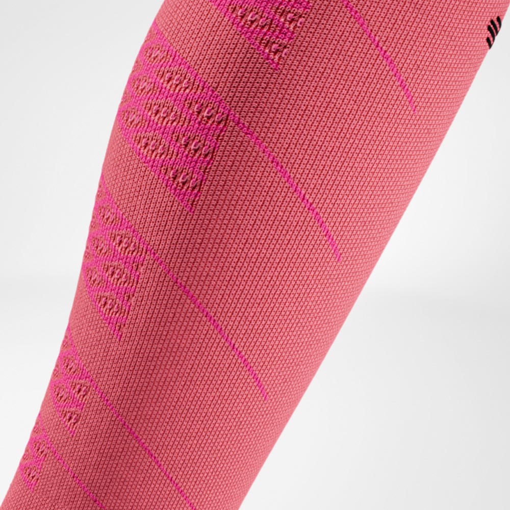 Detailopname van een roze compressiesleeve voor hardlopers. De gebreide structuur zorgt voor gerichte compressie en ondersteuning van de kuitspieren.