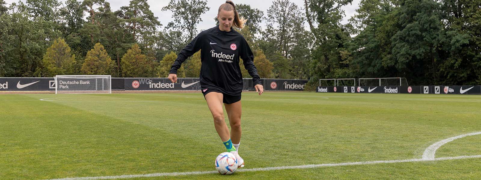 Beveilig enkelverbindingen, dribbelt nog beter: onze sportondersteuning in het voetbal Voetballer met enkelbanden dribbels met een bal op de voet op een gazon
