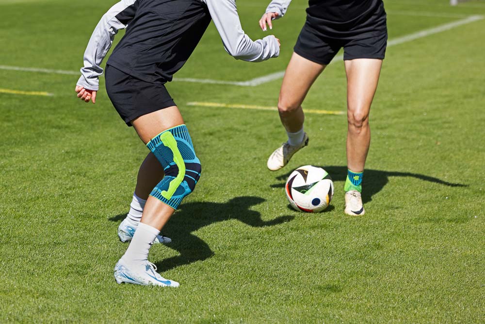 Twee voetbalstertjes nemen het tegen elkaar op. De een draagt ​​een Bauerfeind Sports kniebrace, de ander een Bauerfeind Sports enkelbrace.