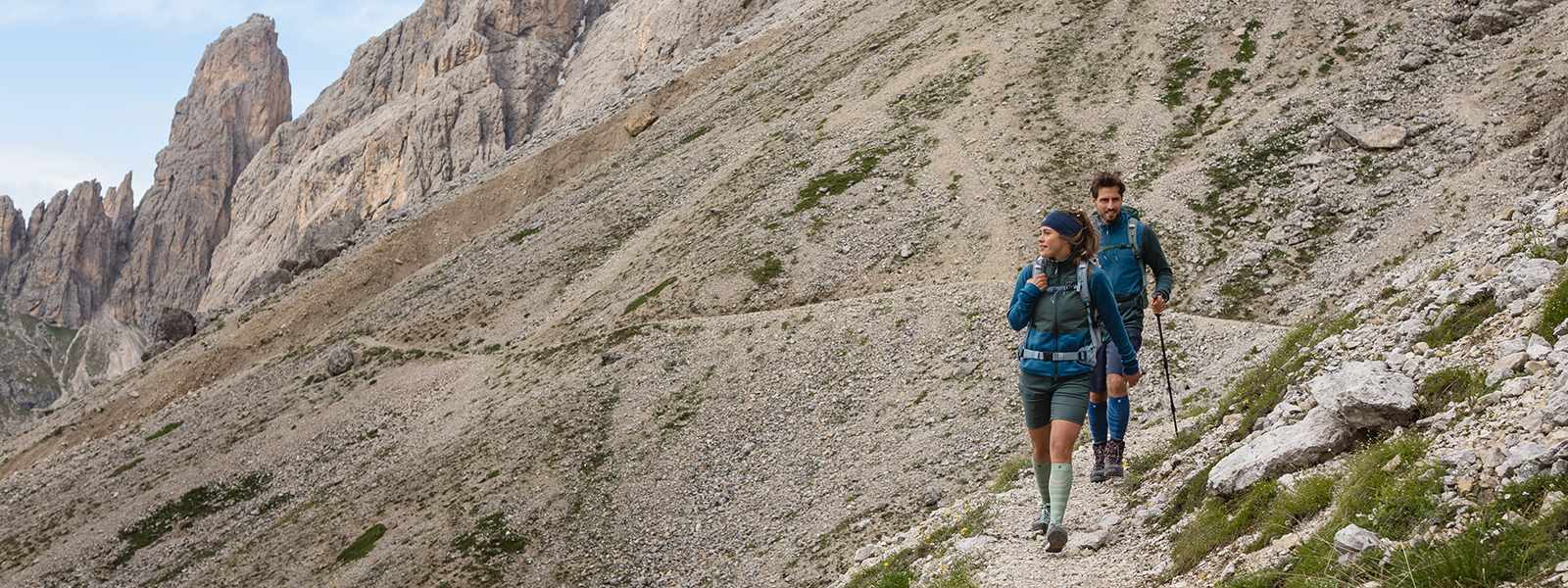 Merino Wanders Socks: Your Companion tijdens de volgende wandeltocht Man en vrouw wandelen een berg af met wandelstokken in de hand en dragen wandelsokken