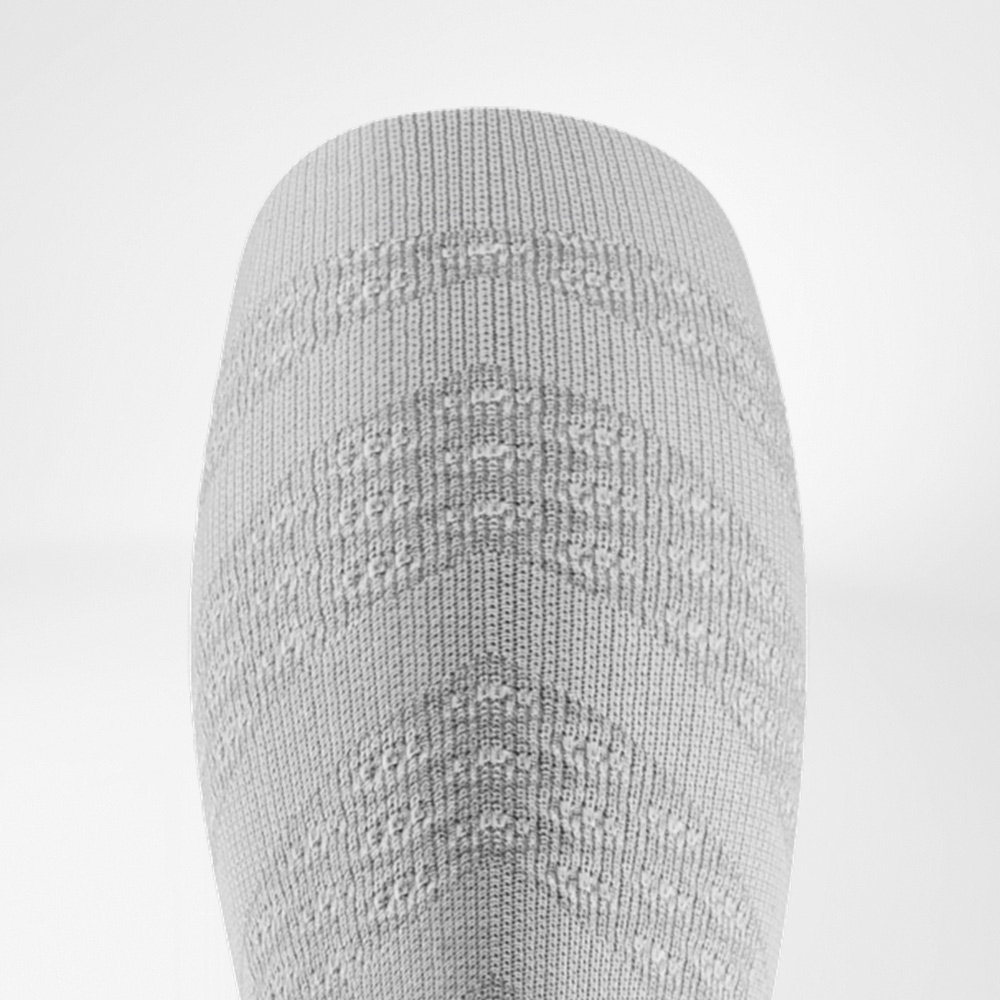 Detailed view of a white compression sleeve with textured surface, applying targeted pressure to the calf muscles.