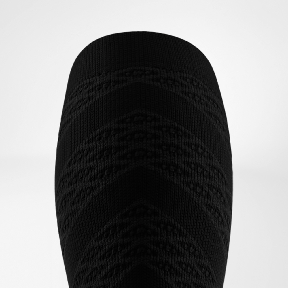 Close-up van de achterkant van een zwarte hardloopsok met geïntegreerde 3D-dots voor gerichte stimulatie en verbeterde spieractivatie.