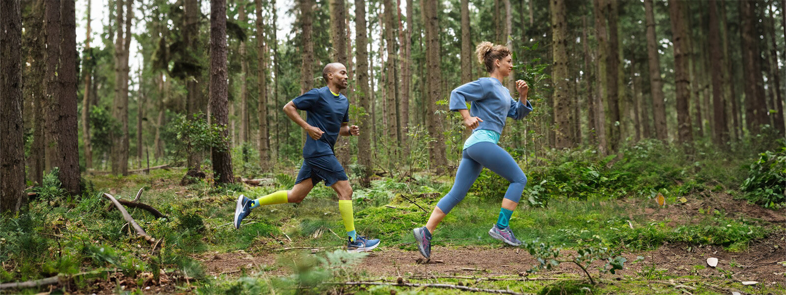 Een vrouw en een man rennen door een dicht bos en dragen verbanden