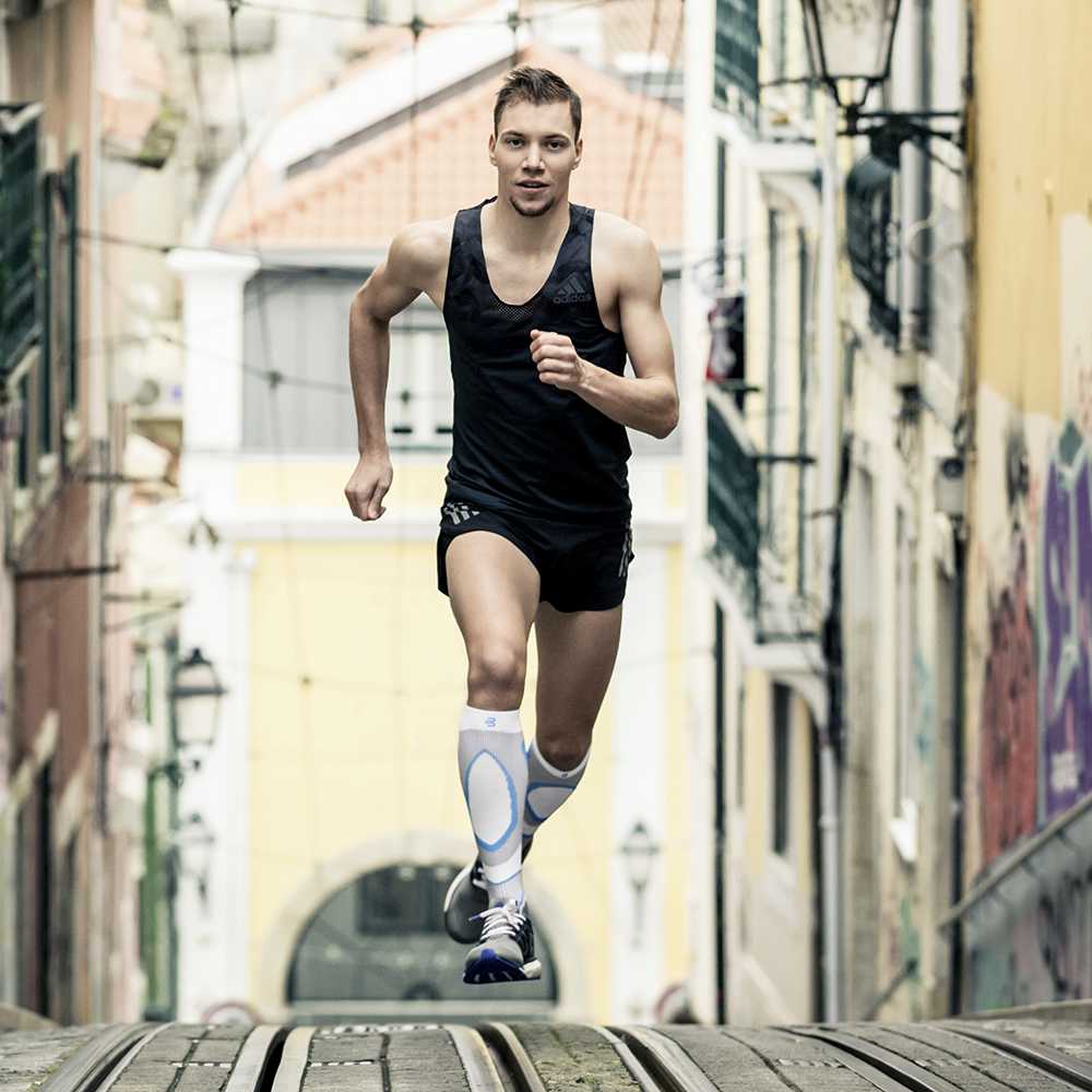 Runner Marcel Bräutigam loopt een toename op met tramrails en draagt ​​witblauwe compressiesokken