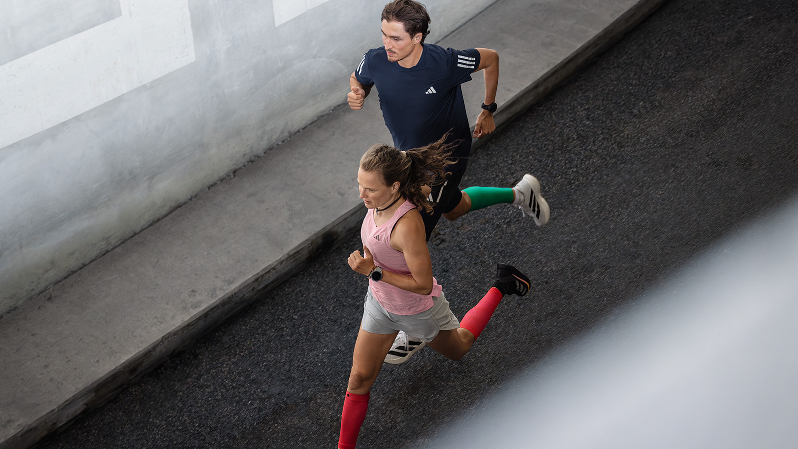 Marathon Training Plan: de ontspannen lange termijn moet altijd de basis vormen voor uw training Twee lopers rennen naast een moderne muur in de stedelijke omgeving en praten