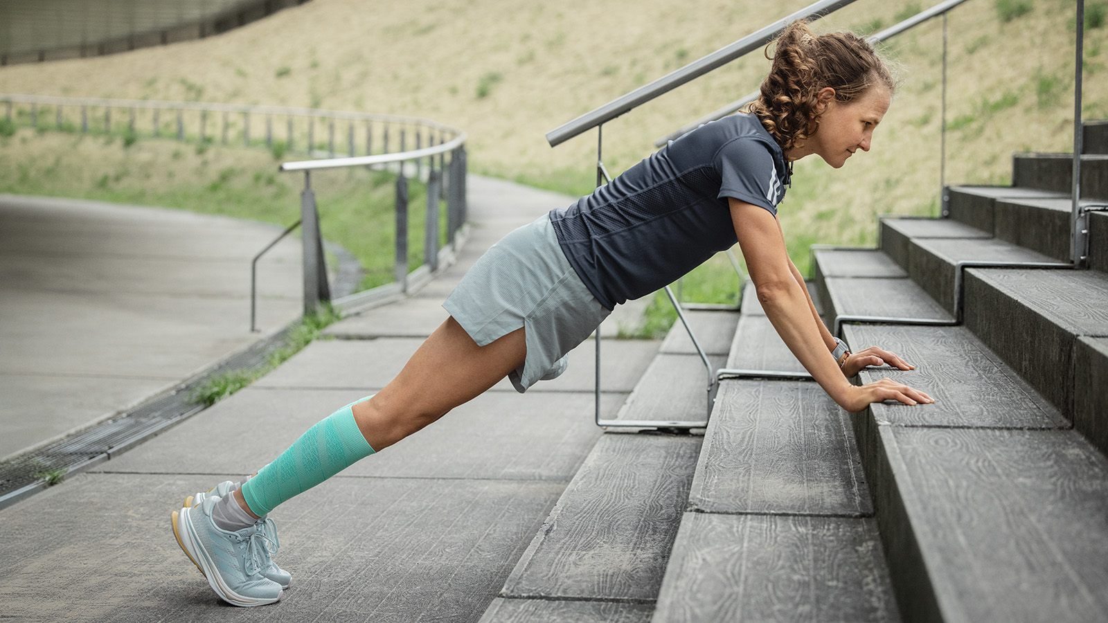 Push-ups gaan zelfs naar buiten Vrouw maakt push-ups op een betonnen vloer op de achtergrond die een man uitstrekt op een muur