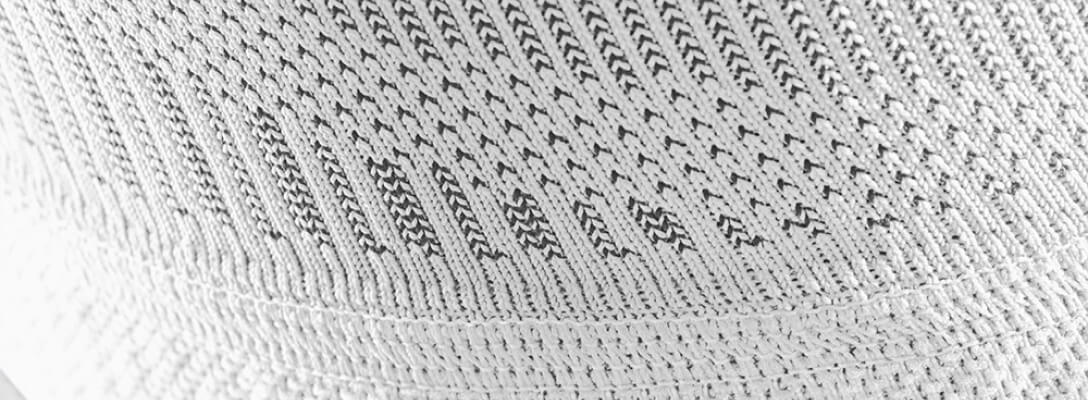 Gedetailleerd beeld van een witte kniehoes met een focus op het breienpatroon