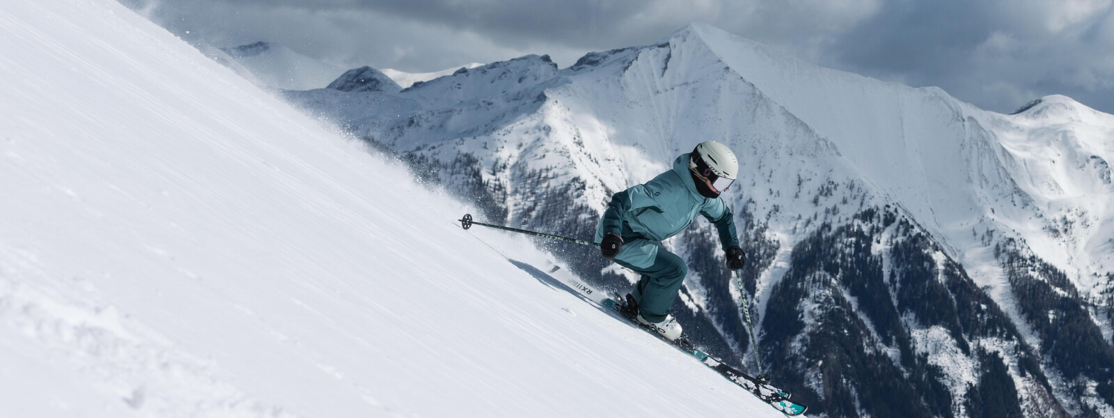 Skiërs drijft een paal af, er zijn met sneeuw bedekte bergen op de achtergrond