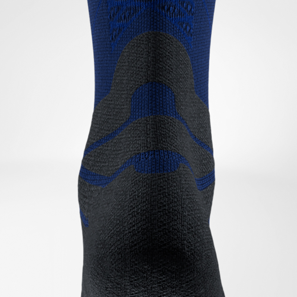 Close-up van een blauw-zwarte hardloopsok van Bauerfeind Sports, achterkant ter hoogte van de achillespees. De opvallende padding beschermt de pees tegen wrijving in de schoen.