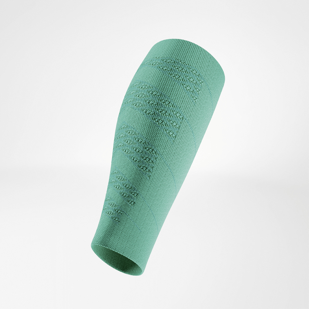 Groene compressiesleeve in schuine zijaanzicht, vrij zwevend. Het fijngebreide materiaal toont duidelijke structuurgedeelten die stabiliteit en ventilatie bieden.