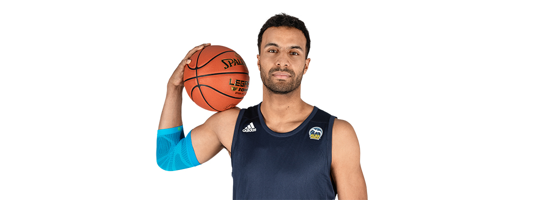 Ellenbogensleeve speelt basketbal Man met basketbal draagt een sportleeve voor de elleboog