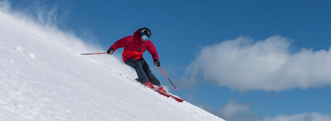 Merino skisokken voor alpineskiën Skiër met rode jas in poedersneeuw tijdens het skiën
