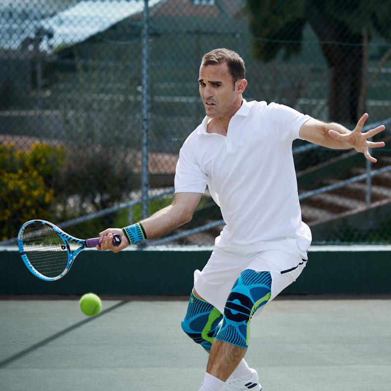Tennisspeler met witte tenniskleding en kniebars op de forehand -beroerte op een hard court