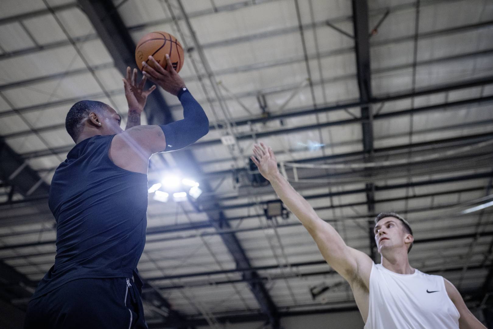 Basketbalspelers met een Blue Armsleeve in Sports Hall probeert de uitgestrekte arm van een tegenovergestelde over te gooien