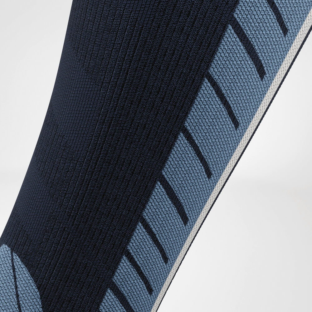 Close-up van de kuit van een blauwe ski-compressiesok met een gedetailleerd breipatroon voor verbeterde ademend vermogen en ondersteuning. Ideaal voor lange dagen op de piste.