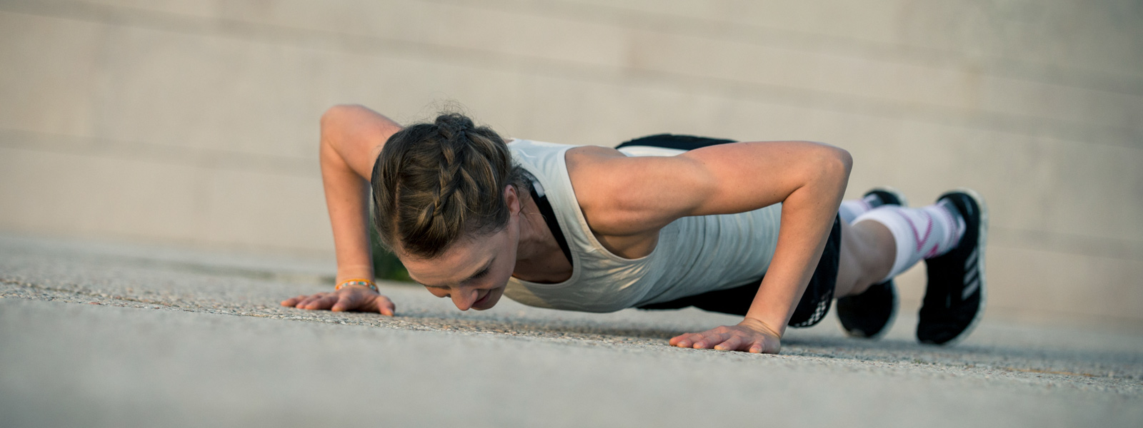 Vrouw zet push-ups op een betonnen vloeraanzicht van diagonaal