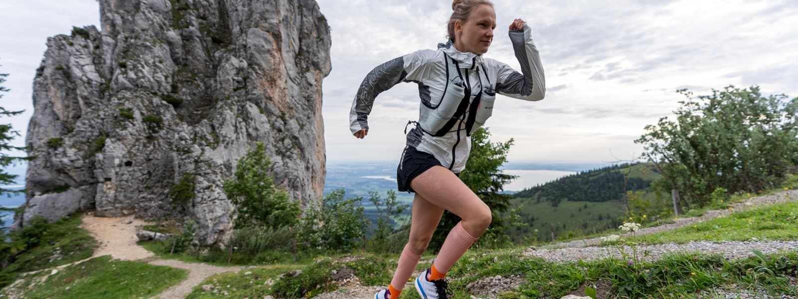 Trail Run Socks Peach In Action Hahner Zwilling rent een berg op en draagt de trailrunsokken in de kleuren perzik