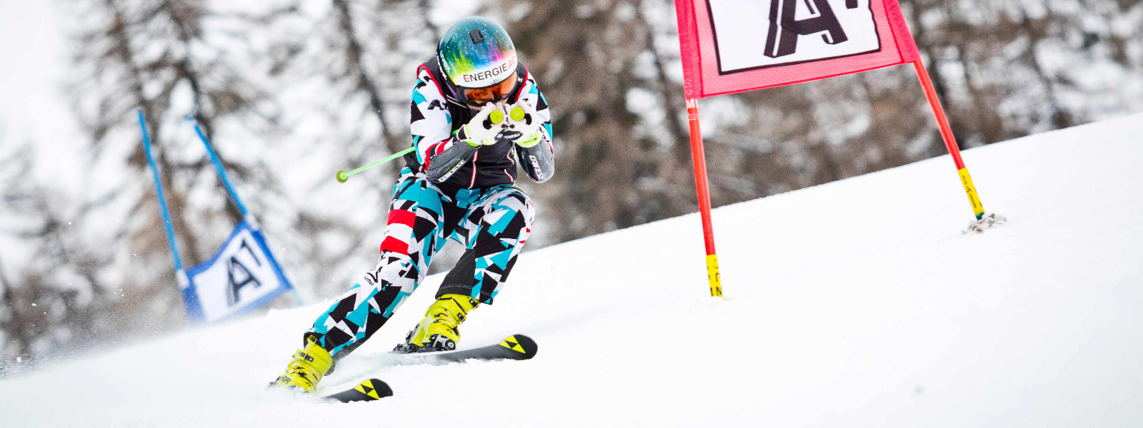 Ski-hardloper in een blauw en witrood racepak gaat in de vertrekpositie na het passeren van een groot doel
