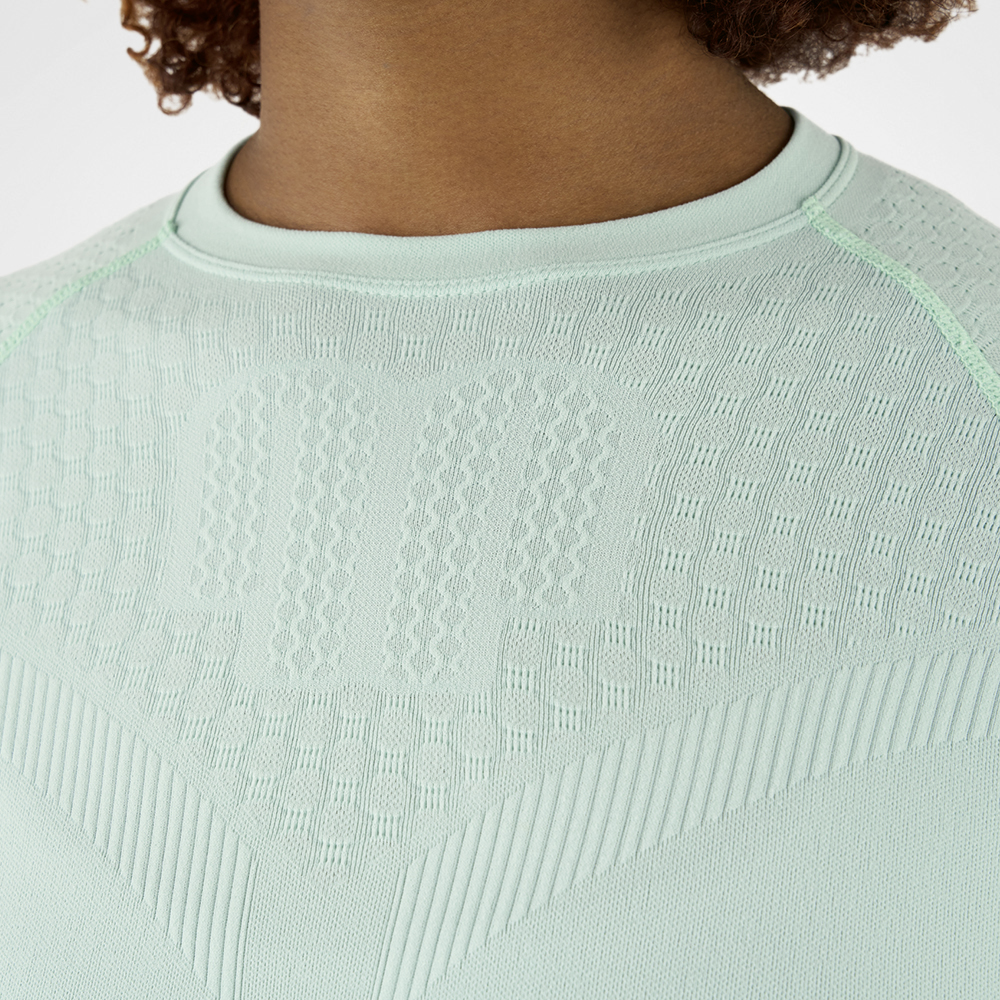 Close-up van een mintgroen compressieshirt met getextureerde stof, die de textuur en details van het materiaal benadrukt.