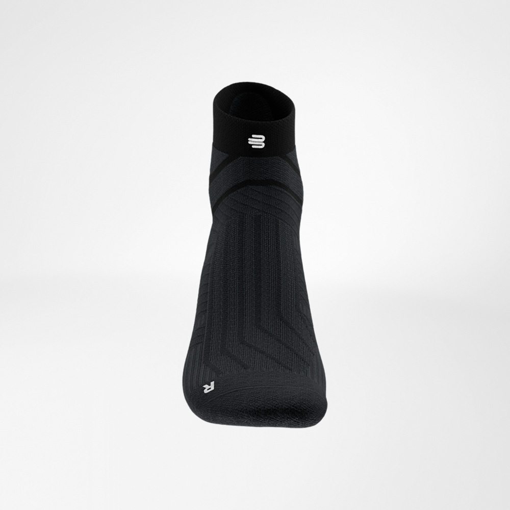 Detail van de boord met logo Close-up van de boord van de zwarte Run Performance Low Cut sok van Bauerfeind, met het witte B-logo en fijne ribstructuur.