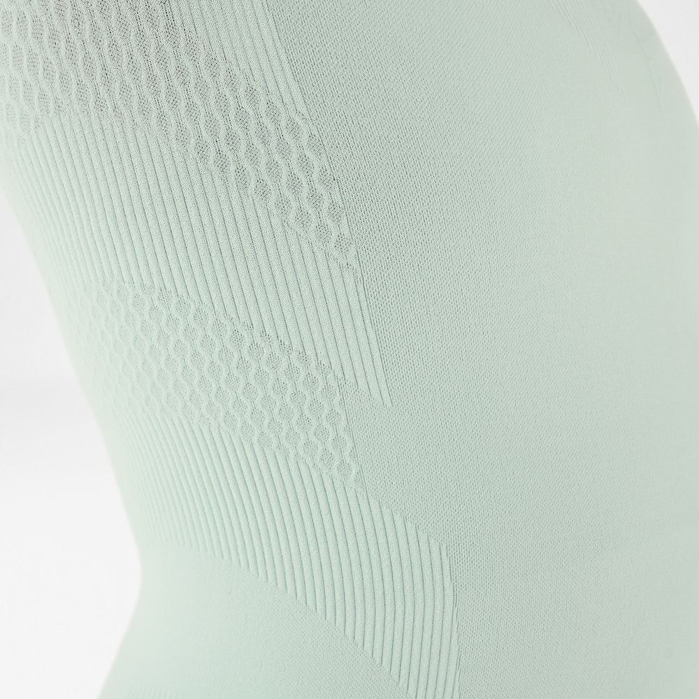 Maglia a maniche lunghe a compressione verde chiaro Close-up van een persoon in blauwe compressiekleding in plank-positie met verschillende textuurpatron