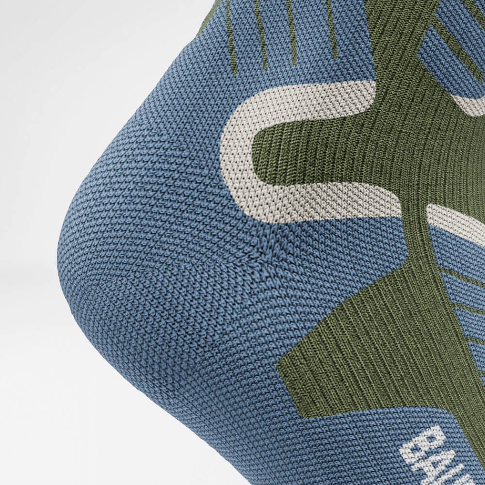 Close-up van de hiel van een groene ski-compressiesok met ademend, ergonomisch breipatroon voor maximale ondersteuning en comfort tijdens intensieve wintersportactiviteiten.