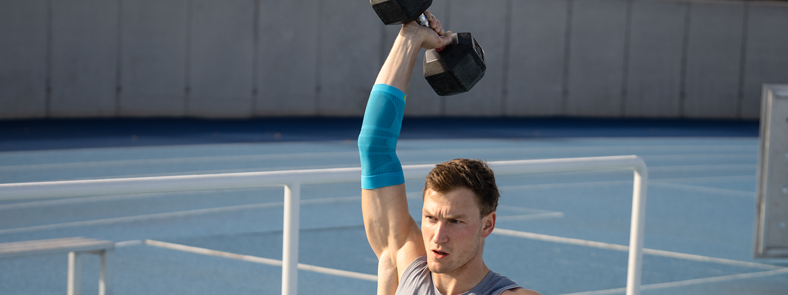Ellenbogen verband tijdens fitnesstraining Thoms Röhler houdt een gewicht omhoog en stabiliseert zijn arm met behulp van een elleboogband