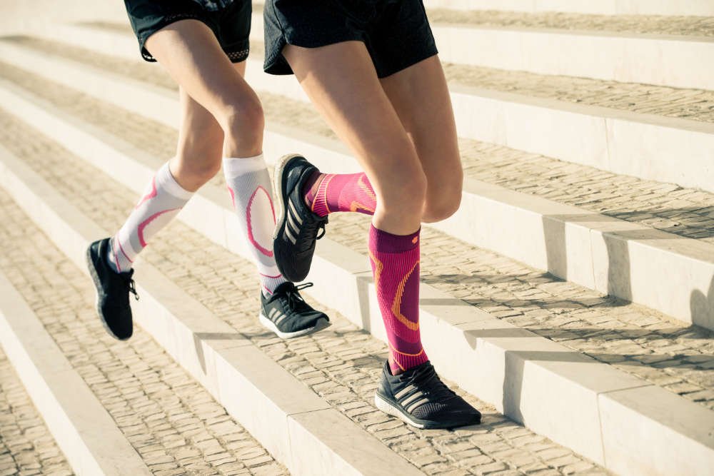 Twee dunne lopers met witte en roze lopende sokken lopen enigszins schuine stenen stappen omhoog