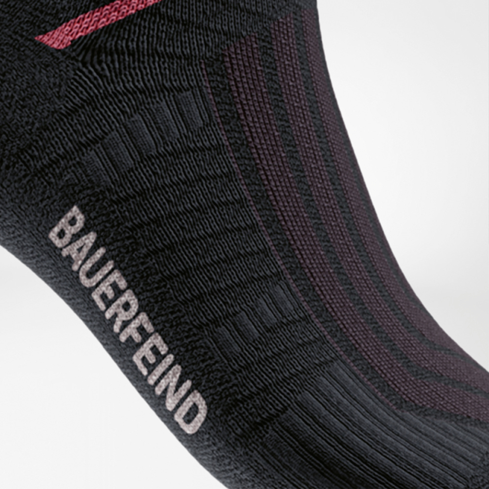 Detailweergave van de Run Performance Midcut Socks in zwart met een rood arch-liftelement. De close-up benadrukt de versterkte compressiezone bij de voetboog voor optimale stabiliteit en steun.