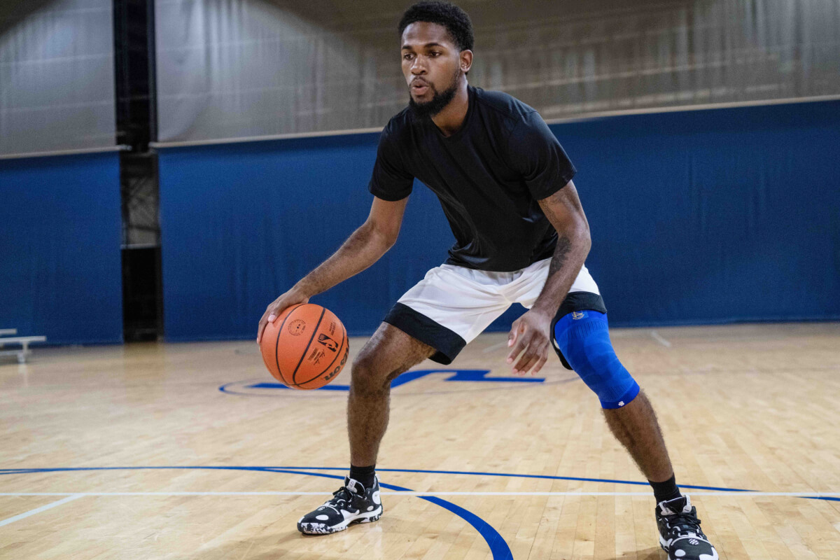 Basketballer dribbelt en draagt ​​de NBA Knee Sleeve Golden State Warriors