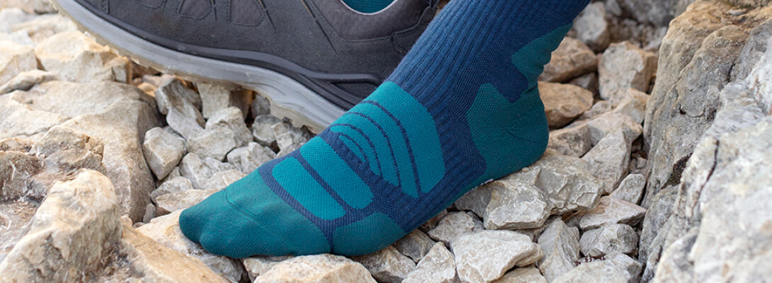 Merino-wandelsokken van middellange lengte donkerblauw tijdens een wandelpauze Gedetailleerd beeld van een voet met middellange merino - wandelsokken op een steenachtig oppervlak - zonder schoen