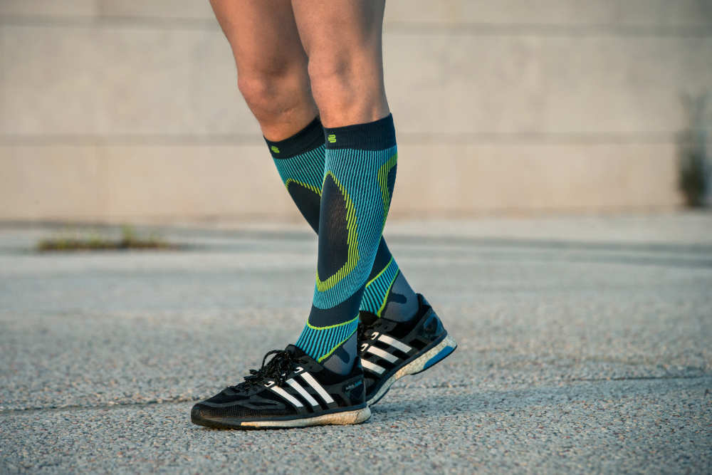 Onderbeen van een loper in close -up met hardlopende lopende sokken met blauw patroon op een betonoppervlak