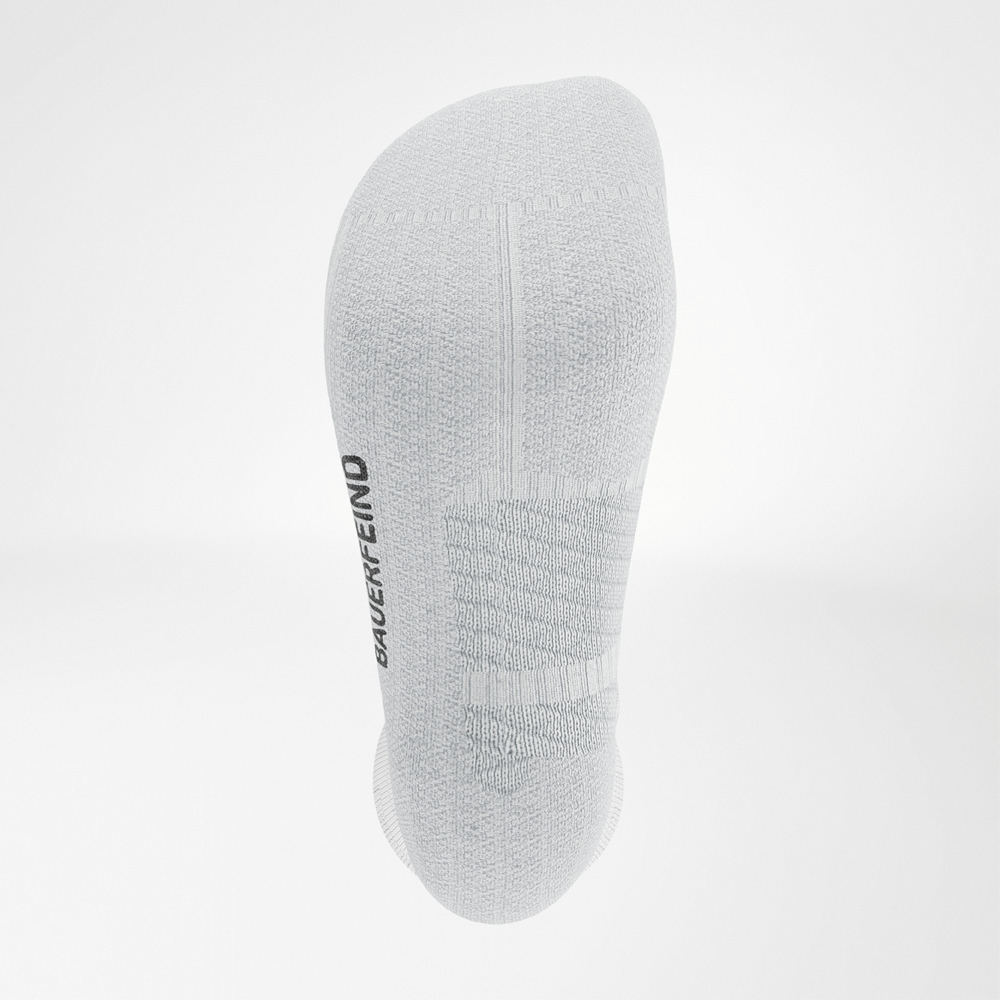 Close-up van de zool van de witte Bauerfeind Run Performance Socks met zichtbare demping en gebreid BAUERFEIND-logo.