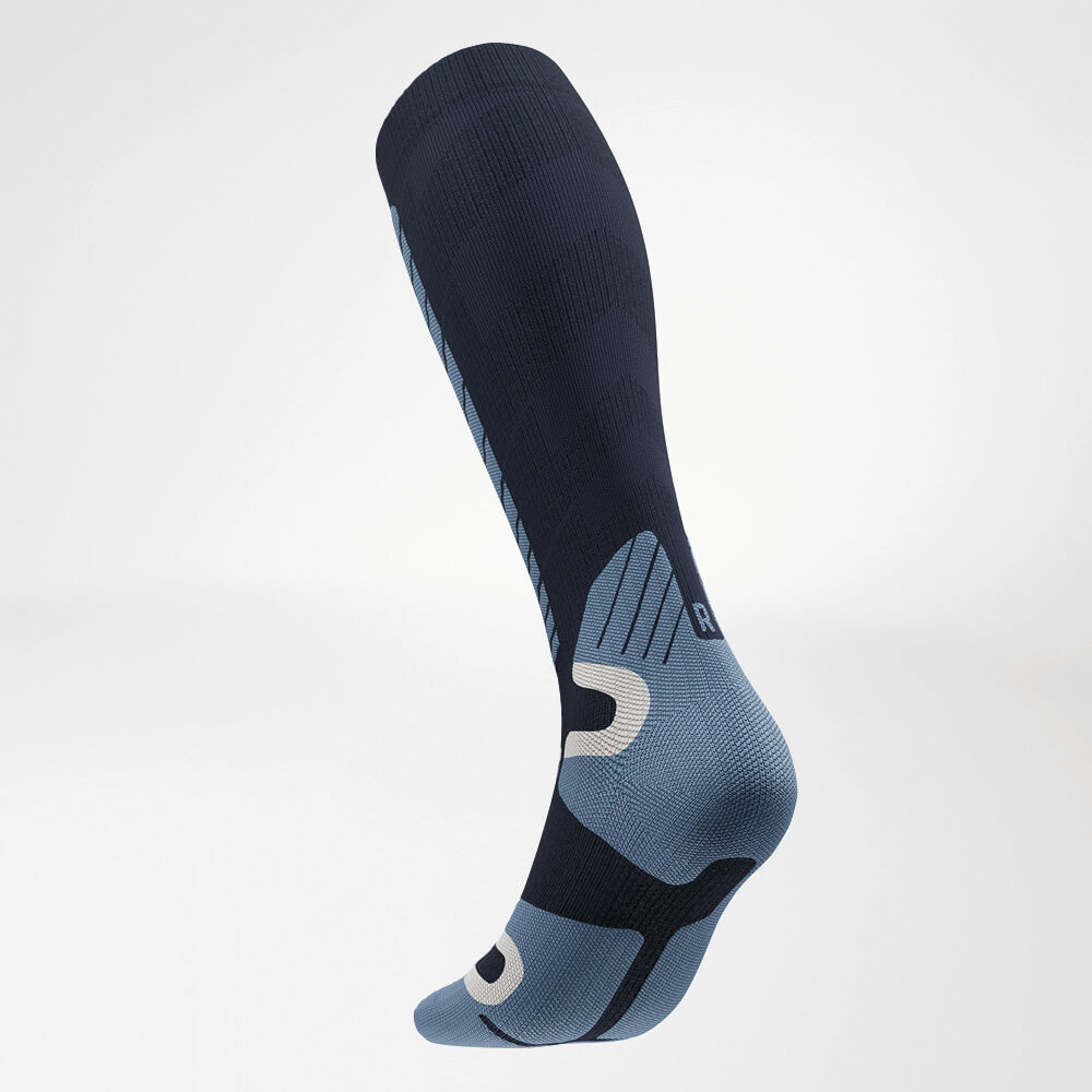 Schuine achteraanzicht van een blauwe ski-compressiesok met ergonomisch ontwerp en versterkte zones voor verbeterde stabiliteit en comfort tijdens wintersport.