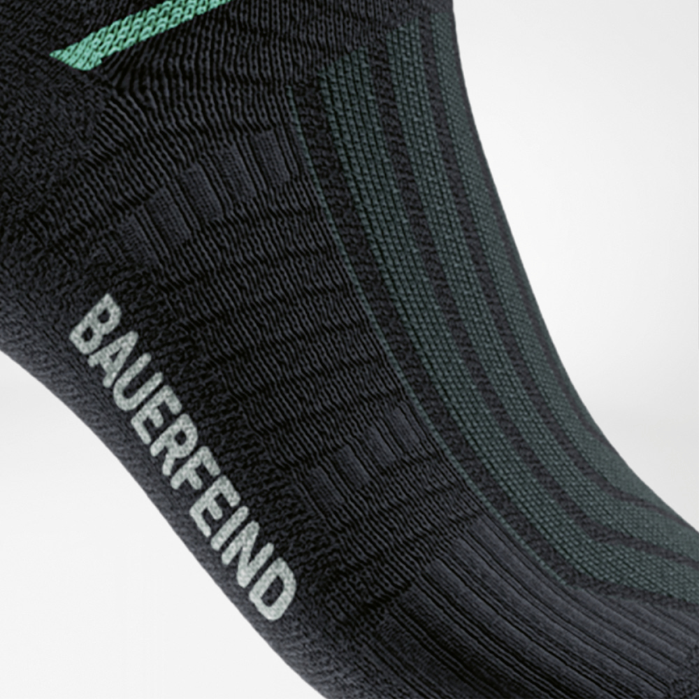 Detailweergave van de Run Performance Midcut Socks in zwart met een groene arch-liftzone. De close-up toont de gestructureerde compressiezone bij de voetboog, die voor gerichte steun en stabiliteit zorgt.