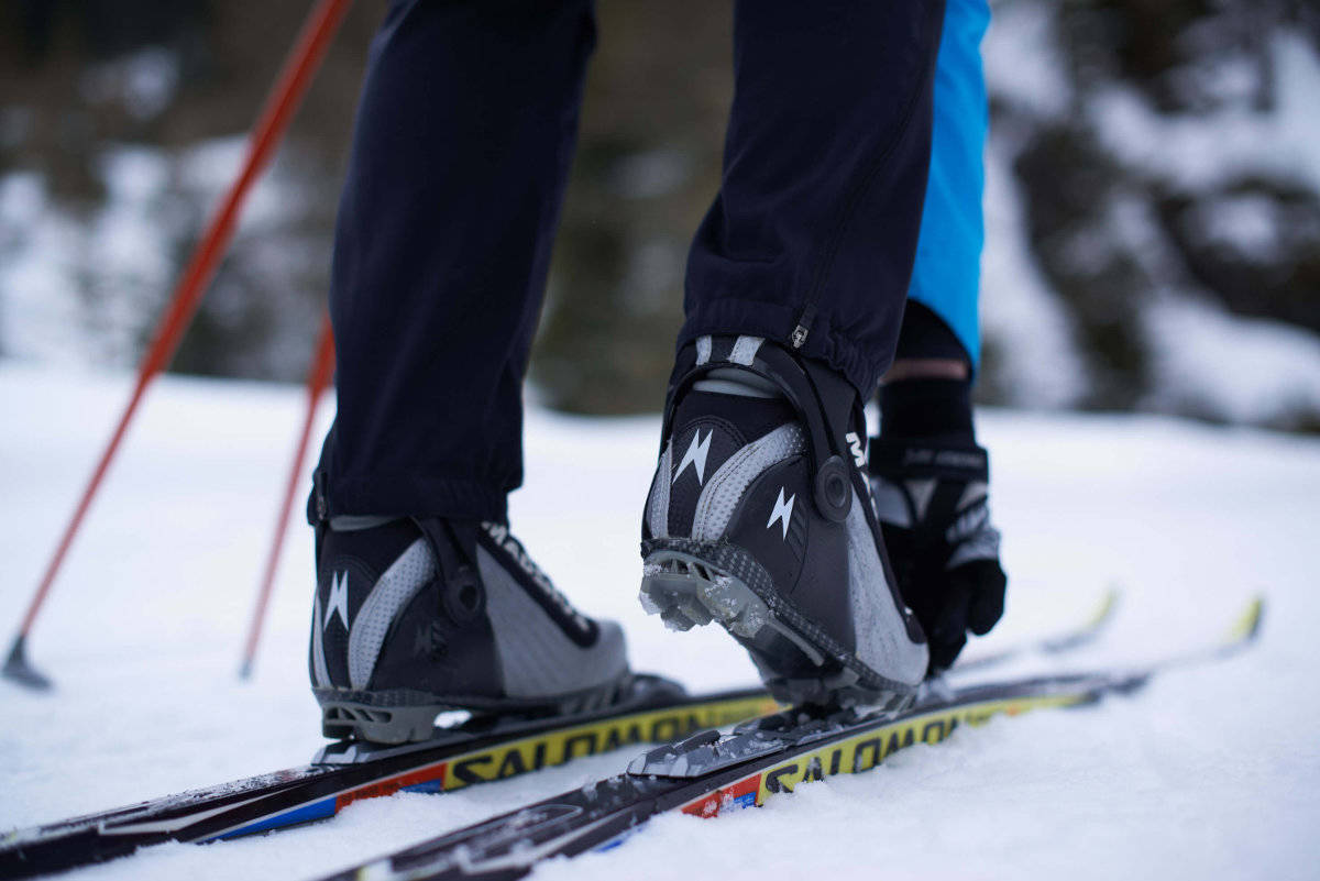 Binding is niet hetzelfde als een binding: kijk of je beter bent of SNS Een langlauf skiër knogelt zijn schoenen aan de ski's close-up