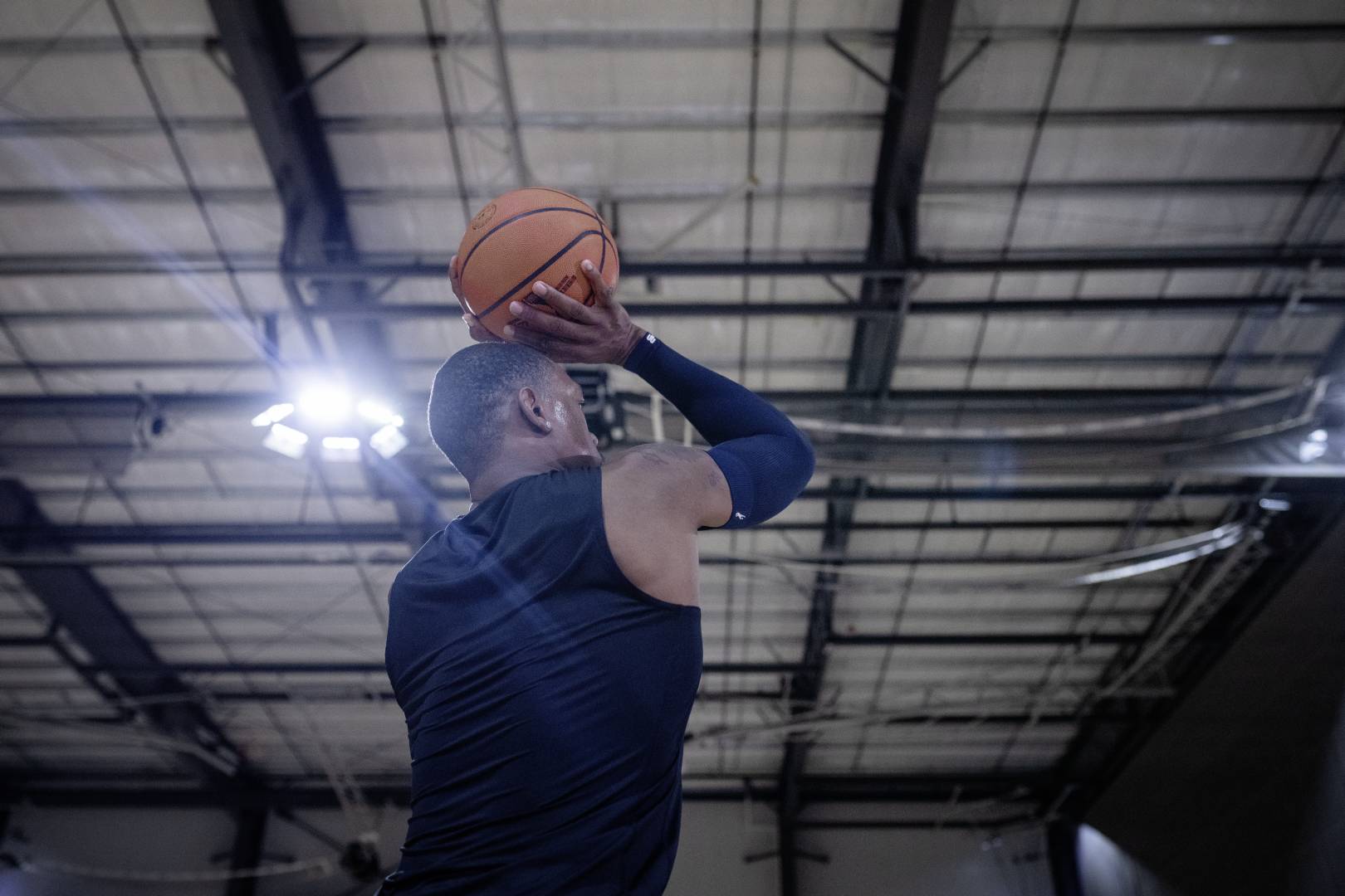 Basketbalspelers met een blauwe armenleeve in een sportzaal beginnen met hun handen boven het hoofd naar de worp