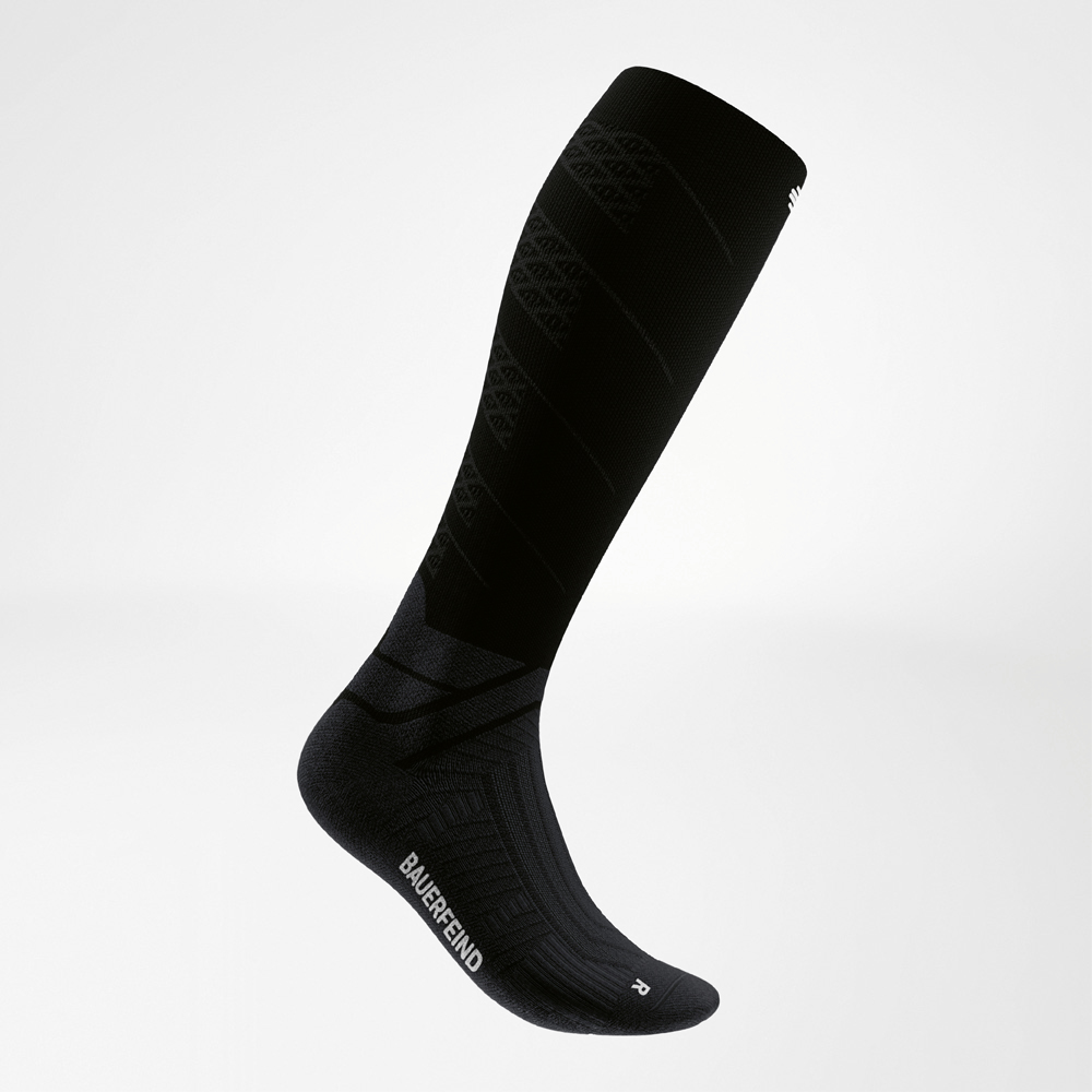 Zijdelingse close-up van een zwarte compressiekous met versteviging op de wreef en enkel voor extra stabiliteit.