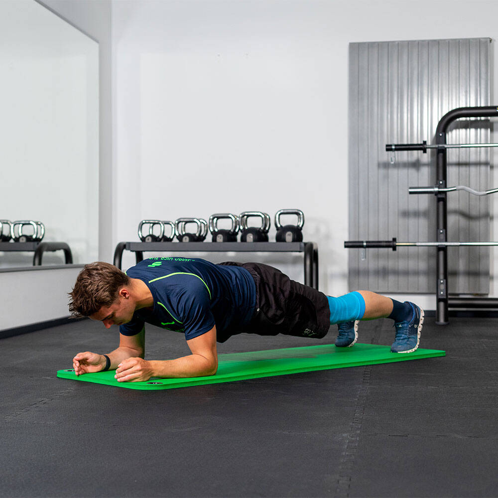 Man in de sportschool houdt een onderarmplank op een fitnessmat