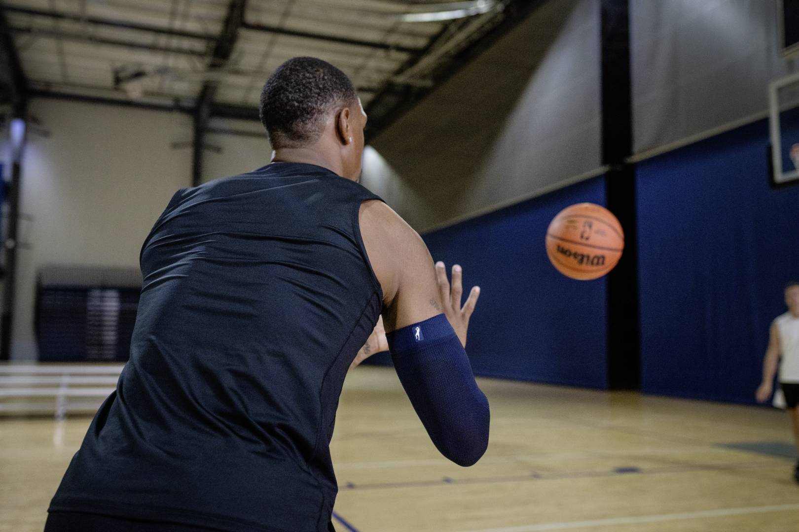 Basketbalspelers met een Blue Armsleeve in Sports Hall wacht op een bal die door een andere speler naar hem wordt gegooid