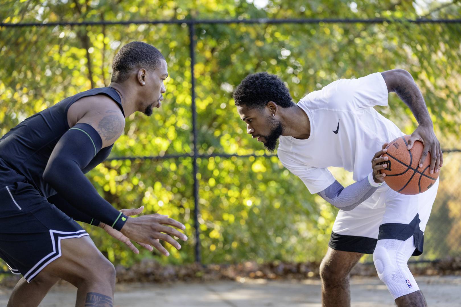 Streetball -speler in witte spelkleding probeert zijn tegenstander te spelen in zwarte spelkleding