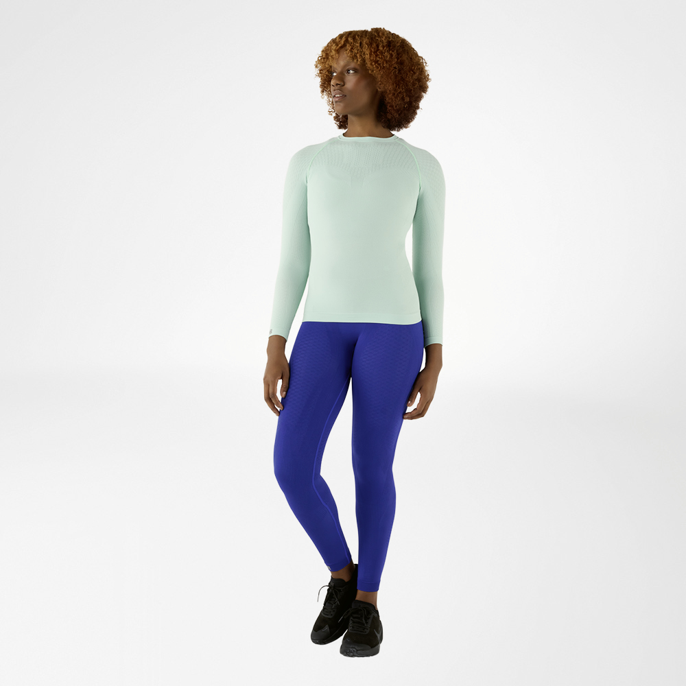 Vrouw in een blauw, nauwsluitend langmouwshirt en blauwe compressiebroek, vooraanzicht