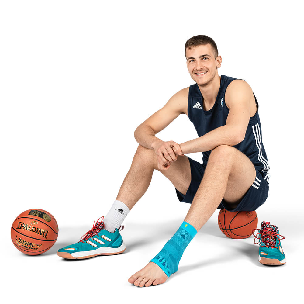 Spieler sitzt auf einem Basketball mit Sleeve