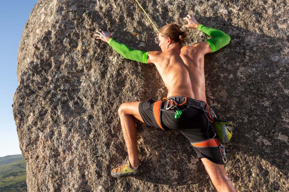 Klimmen met vrije romp en groene arm-mouwen hangt aan een rots en probeert te trekken in de achtergrond Green Mountains is te zien