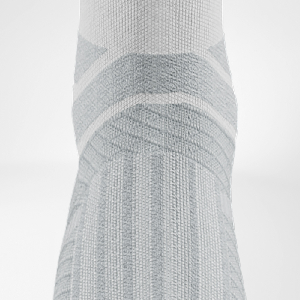 Detailopname van de enkelzone van de witte Run Performance Socks met anatomische demping en steunstructuren.