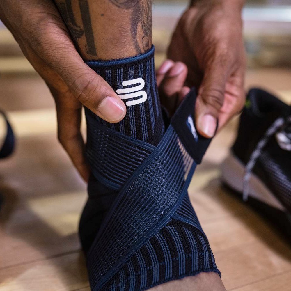 Stap voor stap stabiliteit. Close-up van een zwarte enkelbrace met geïntegreerde steunzones en een elastische band voor individuele aanpassing.