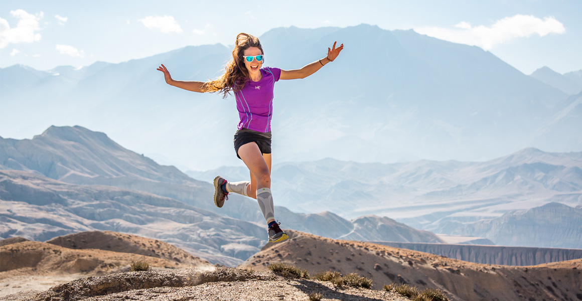 Vrouw met Wadensleeves maakt springen en is blij met bergketen