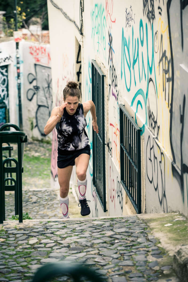 Twee vrouwen lopen krachtig door een oude stadstraat met kleine balkons