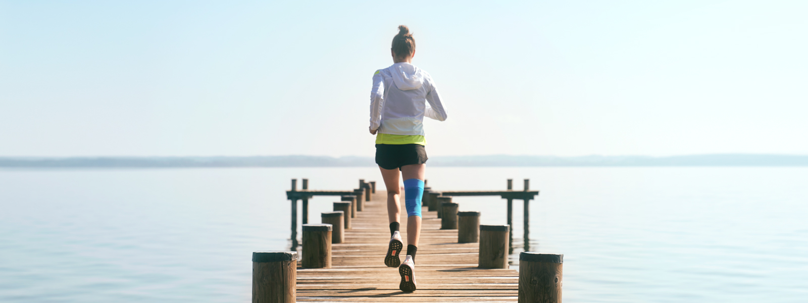 Anna Hahner rent met haar sportcompressie knieondersteuning via een steiger naar het meer