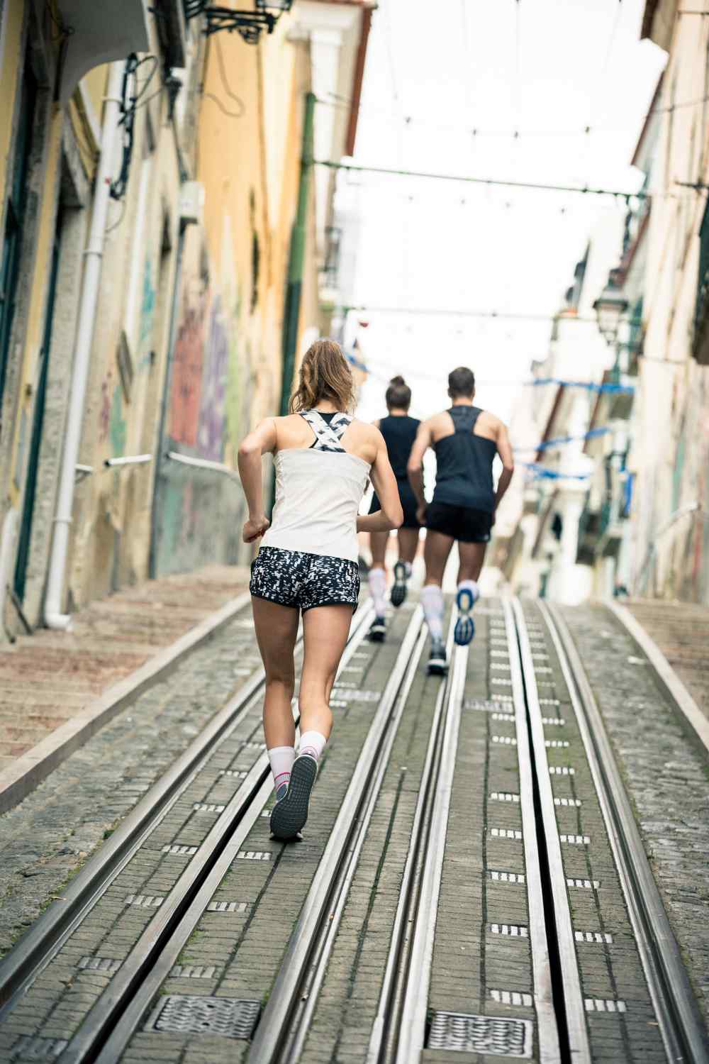 Twee lopers en een hardloper lopen een tramlijn in een stad